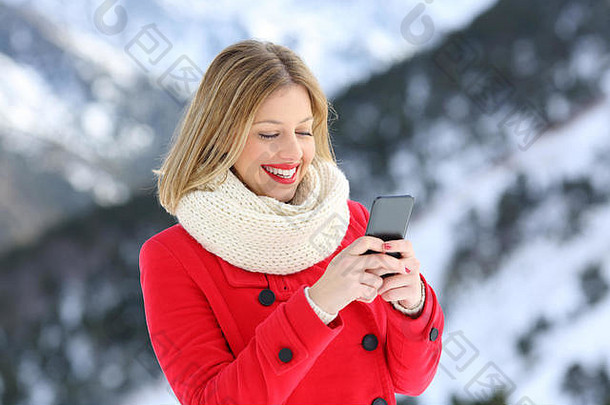 红衣女人在冬天使用智能手机，背景是雪山