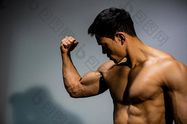 一位健身模特将二头肌向肌肉方向弯曲。中等特写镜头。
