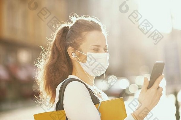 生活冠状病毒流感大流行时尚的女蓝色的上衣医疗面具手提包视频聊天在户外城市街