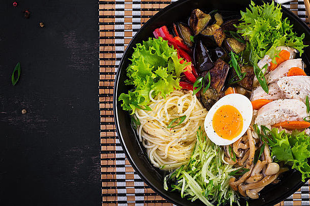 日本拉面汤，黑色木质背景，配鸡肉、鸡蛋、石磨蘑菇和茄子。相扑汤。俯视图