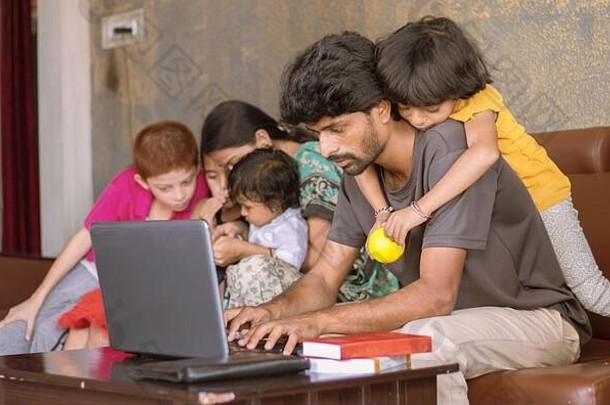 孩子或孩子骑在父亲背上玩耍，父亲忙着用笔记本电脑工作时打扰孩子-新冠肺炎期间在家或WFH工作的概念