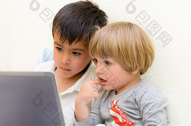 两个孩子盯着笔记本电脑