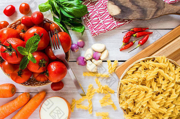 意大利烹饪准备平面图，白色木桌上有意大利面、西红柿和其他配料-烹饪和健康食品概念图。