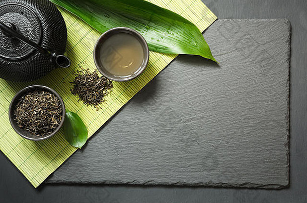黑石板背景的日本绿茶。红茶壶和绿茶碗。典礼具有空间的俯视图。