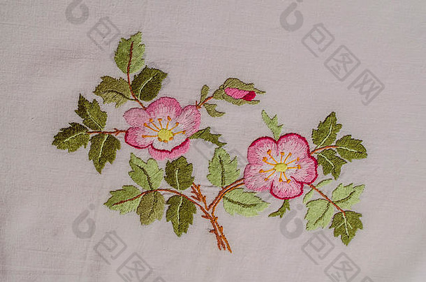 亚美尼亚埃里温，2018年6月4日：小枝上开着粉红色的花，茶玫瑰上有花蕾和叶子，在粗糙的棉布上绣着缎子