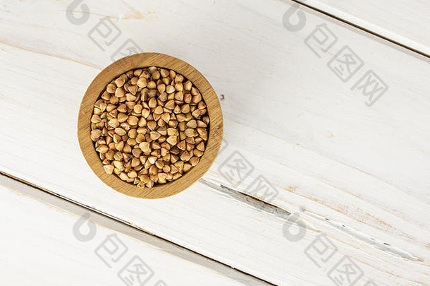 大量未的棕色<strong>荞麦</strong>颗粒放在一个木碗里，平铺在白木上