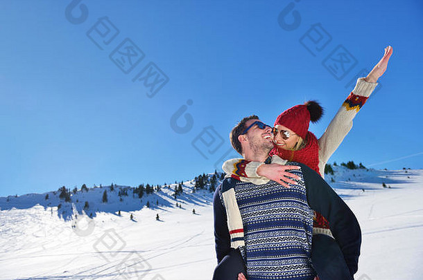 这对年轻夫妇在雪上玩得很开心。山上的快乐男人背着他微笑的女朋友。