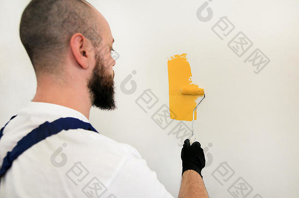 建设工人完成改造公寓专业画家油漆辊刷绘画墙黄色的颜色