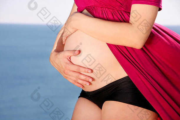 美丽<strong>的</strong>孕妇和女士站在自然环境中，抱着她怀孕<strong>的</strong>肚子。等待婴儿。<strong>妈妈牵</strong>着贝尔<strong>的手</strong>