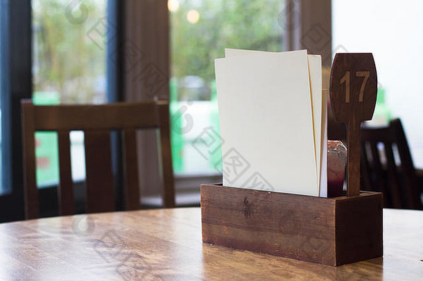 带有番茄酱木盒和白色空白菜单页的餐厅餐桌设置的前视图