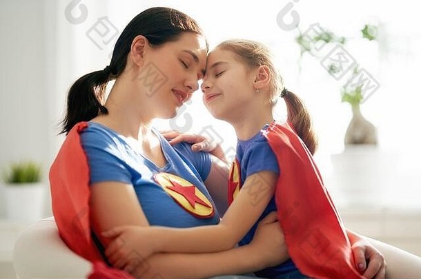 妈妈和她的孩子一起玩。穿着超级<strong>英雄</strong>服装的女孩和妈妈。妈妈和孩子玩得很开心，微笑着拥抱着。家庭假<strong>日</strong>和聚会