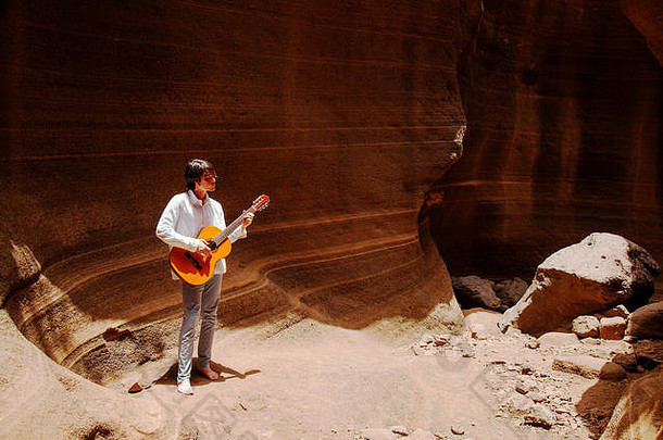 格兰加那利，特米萨斯和阿奎姆斯之间的巴兰科·德拉斯瓦卡斯峡谷光滑的墙壁，少年弹吉他