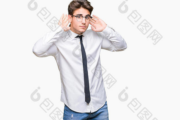 这位年轻的商人戴着眼镜，站在孤立的背景上，试图听到双手合耳的手势，对八卦很好奇。听力问题，聋人