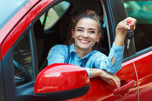 年轻的快乐的女人坐着车键手概念租金车