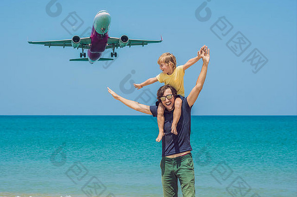 父子俩在海滩上看著降落的飞机玩得很开心。带着孩子坐飞机旅行