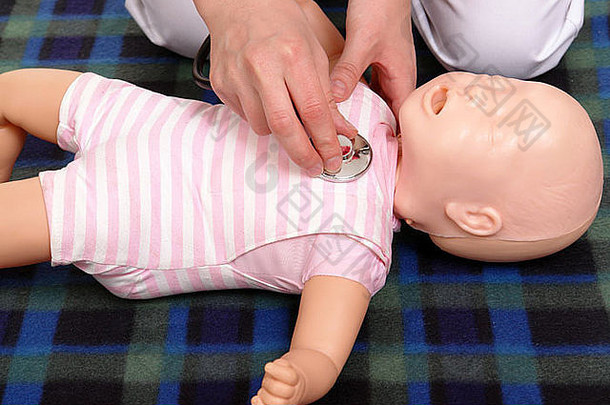 急救教练使用婴儿假人演示如何使用听诊器检查婴儿