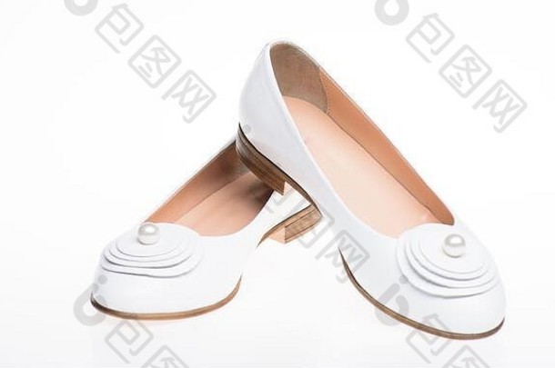 白色背景上的白色皮革制成的鞋，隔离。极简主义概念。一双时尚舒适的芭蕾舞鞋。以珍珠珠为装饰的平底女鞋。