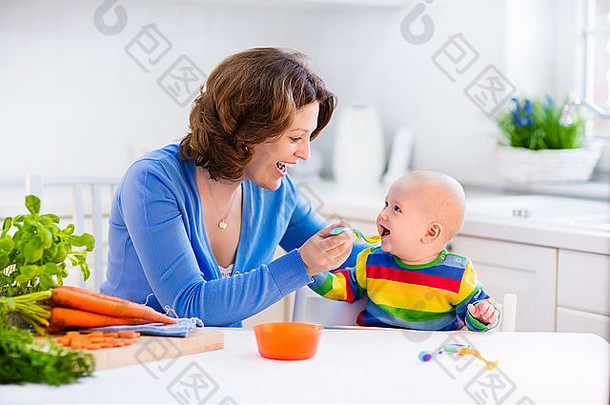 母亲喂养孩子。给小孩子的第一种固体食物。新鲜的有机胡萝卜做蔬菜午餐。婴儿断奶。