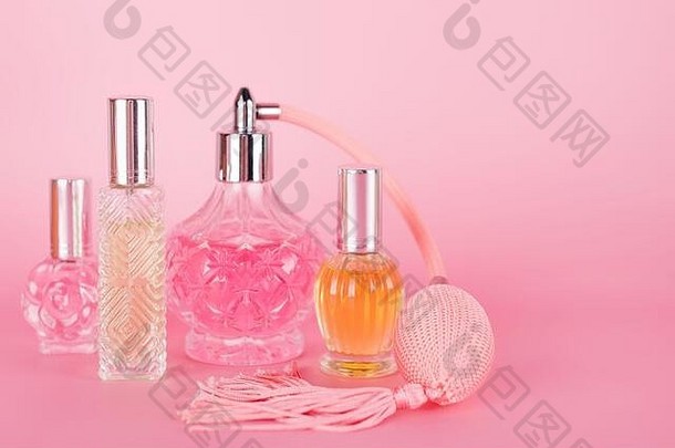 粉红色背景上的不同透明香水瓶。芳香香精瓶。香水、化妆品、香水系列。文本的可用空间。