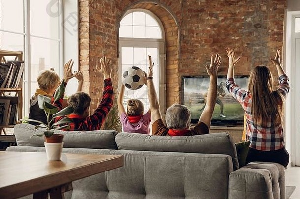 胜利兴奋、快乐的一家人在家里的沙发上看美式足球赛、冠<strong>军</strong>赛。球迷们为最受欢<strong>迎</strong>的国家队欢呼。女儿，爸爸和爷爷。<strong>运</strong>动、电视、娱乐。