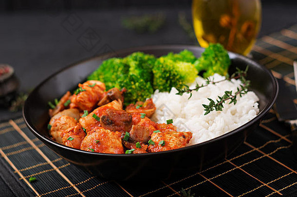 块鸡角蘑菇红烧番茄酱汁煮熟的西兰花大米适当的营养健康的生活方式饮食菜单