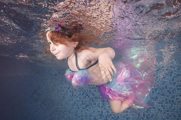 在游泳池水下玩耍的女孩在气泡中漂浮和旋转。健康的家庭生活方式和儿童水上运动活动。儿童发展
