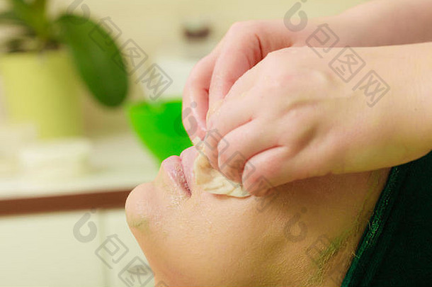 美容师在沙龙里擦去女人脸上的绿藻泥<strong>面膜</strong>。spa理念中的美容、放松、<strong>护肤</strong>、健康。