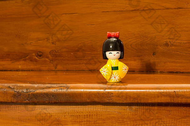 传统的黄色木制日本玩具（souvenier），木质背景。