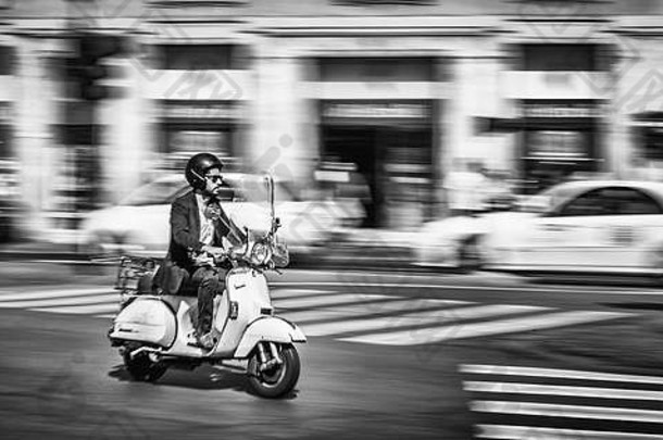 年轻的男人。骑摩托车城市街罗马意大利捕获单色运动