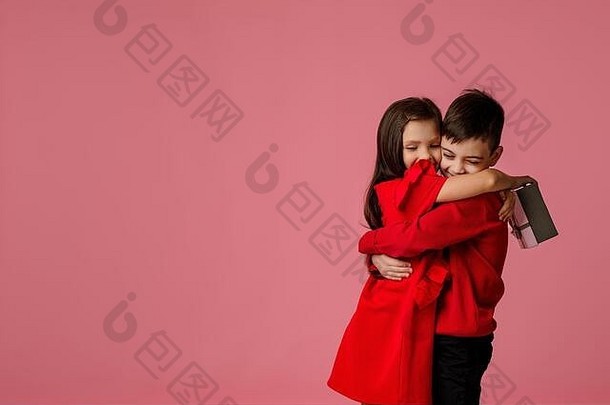 一对幸福的小夫妻，一对小女孩和一对小男孩，在粉红色背景下，他们抱着一个礼物盒。情人节