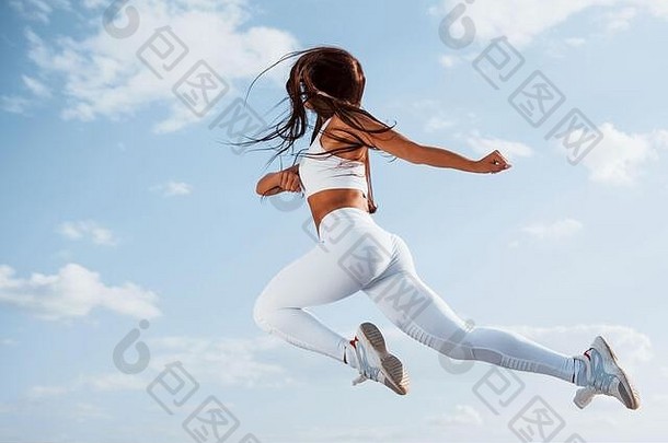 在天空中。穿着白色运动服的女跑步者正在健身