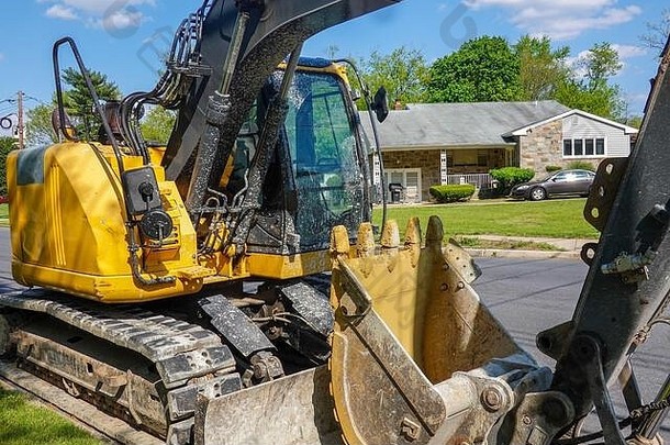 特写镜头一边视图黄色的重设备挖掘机停一边住宅街前面房子