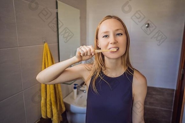 年轻的白人妇女用竹牙刷刷牙