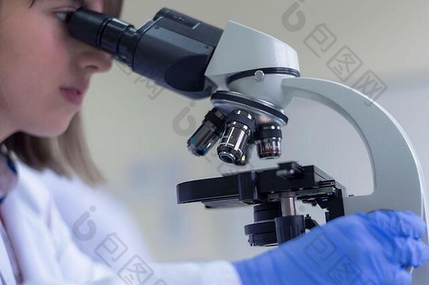 年轻的女科学家显微镜实验室研究微生物分析医学