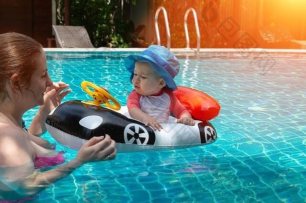 年轻快乐的妈妈穿着粉色比基尼，在游泳池里玩得很开心，还钓到了<strong>宝宝</strong>。一个快乐的小孩坐在汽车形状的充气船上。夏季海上休闲。