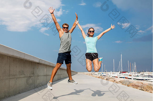 穿着运动服的幸福夫妇在码头上跳跃