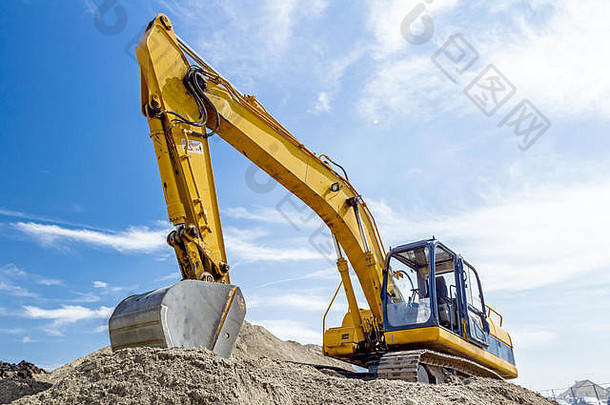 在施工现场，黄色挖掘机正在通过将地面拉到堆上的方式来堆土，项目正在进行中。