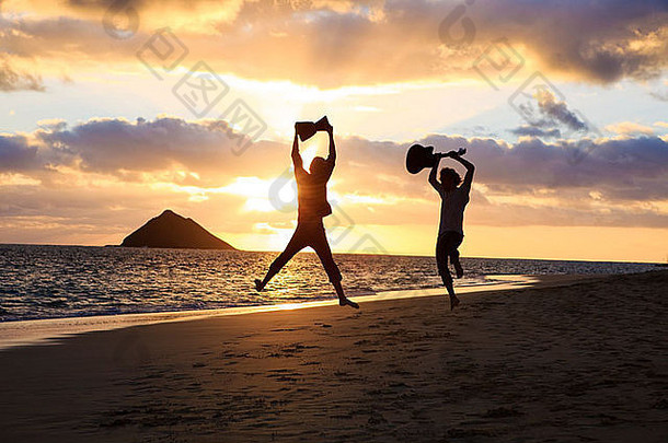 夏威夷海滩日出时，一对孪生兄弟的剪影，鼓和吉他在空中跳跃