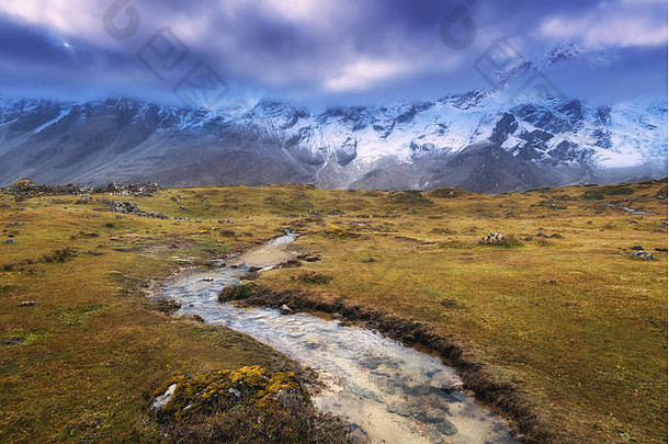 山上有白雪覆盖的山峰，小河，黄色的草和日落时多云的天空。山谷。尼泊尔<strong>历险</strong>记。和Himalay在一起的精彩场面