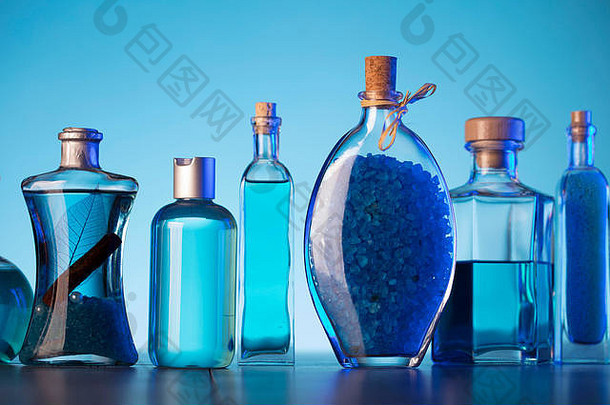 沐浴和水疗概念。玻璃桌和蓝色背景上的Difeerent化妆品。