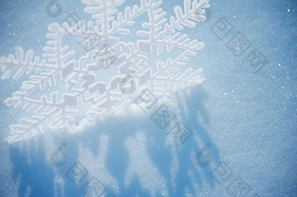 一个风格化的雪花形状投射阴影在一个清新闪亮的冬季雪花背景上