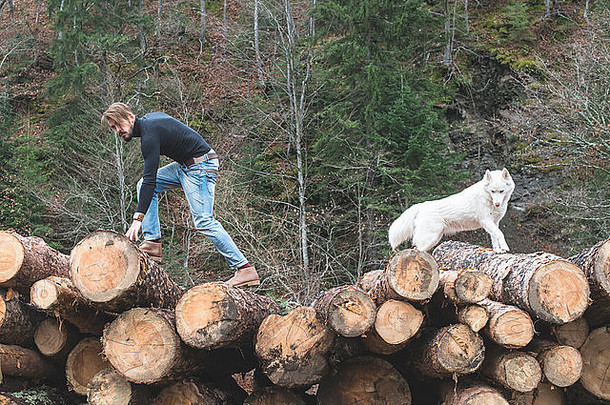 年轻人和狗在森林里的圆木上玩耍。时尚风格