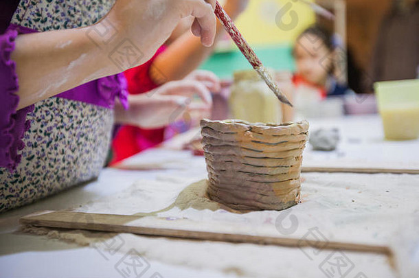 在陶艺工作室的陶艺课上，孩子们用毛笔粘土画手的特写镜头