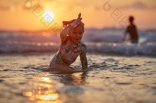 快乐快乐的女孩在海边玩耍。日落时在海滩上玩耍的小女孩