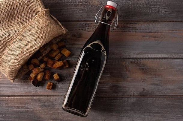 顶视图：木制背景上，的传统俄罗斯kvass装在瓶子里，饼干装在袋子里。夏日健康清爽饮料