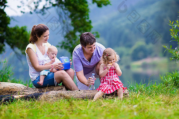 家庭夏天徒步旅行年轻的父母孩子们徒步旅行湖妈妈。父亲孩子们野餐在户外