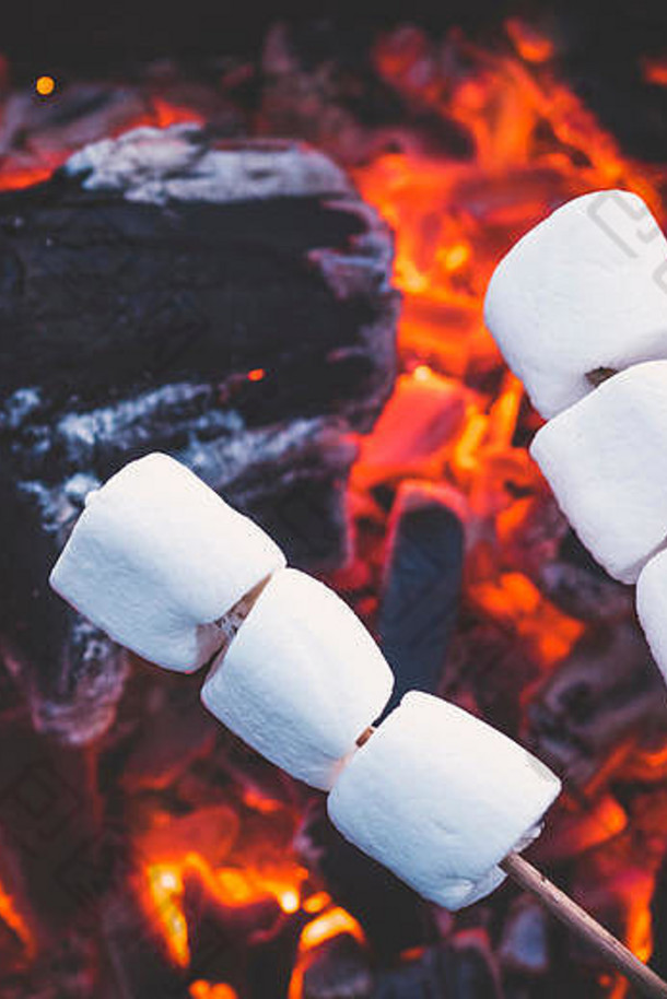 红火上烤着的一套甜棉花糖。串上的棉花糖在炭火上烤。