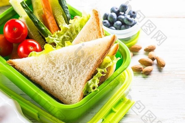 午餐盒里有三明治、蔬菜、浆果和坚果。