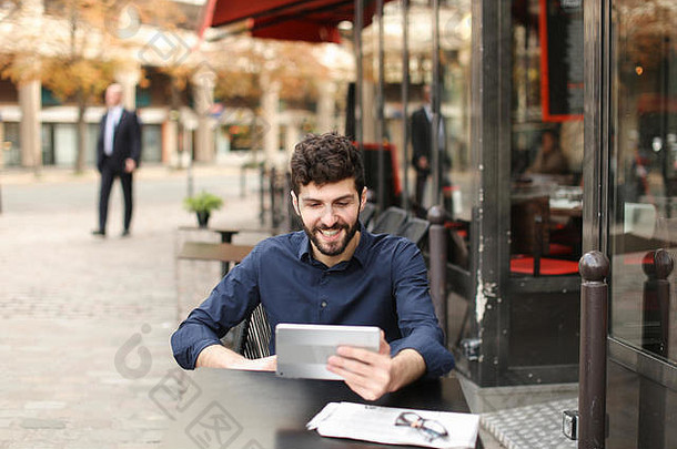 一名<strong>心怀</strong>不满的男子在街边咖啡馆用平板电脑玩网络游戏。