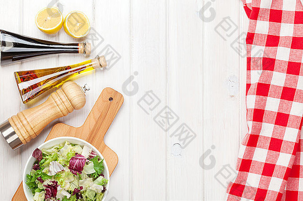 白色木桌上放着新鲜健康的沙拉和调味品。使用空间从上方查看